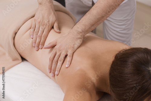 A professional masseuse providing a relaxing back massage to a client in a serene indoor setting.