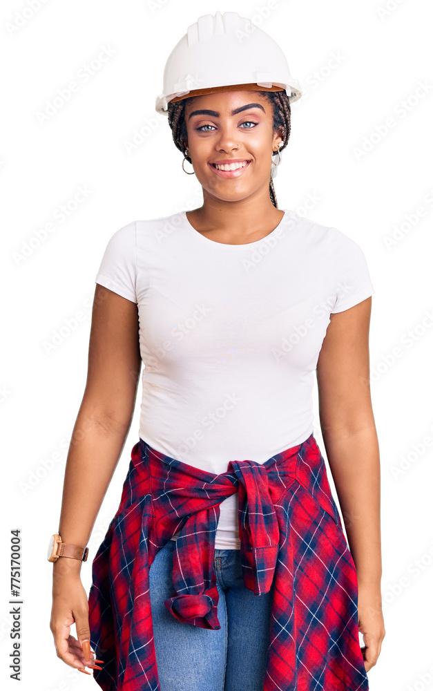 Young african american woman with braids wearing hardhat and builder clothes looking positive and happy standing and smiling with a confident smile showing teeth Young african american woman with braids wearing hardhat and builder clothes looking positive and happy standing and smiling with a confident smile showing teeth