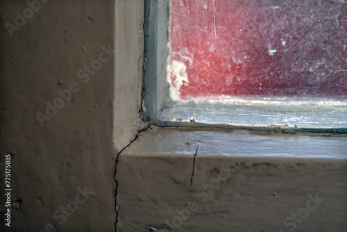 THE CORNER OF AN OLD WINDOW WITH A CRACKED FRAME AND DIRTY GLASS