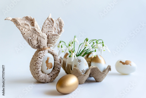 Minimal Easter concept. Festive spring mood, paper box with Easter eggs in light colors and snowdrop flowers.