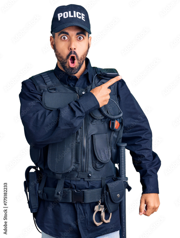 Fototapeta premium Young hispanic man wearing police uniform surprised pointing with finger to the side, open mouth amazed expression.