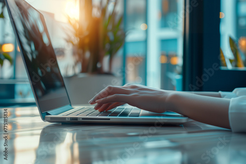 A business professional woman typing on their laptop, with office windows background, focusing on hands with a blurred office