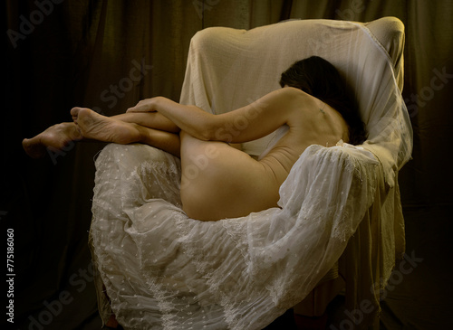 woman without clothes lying in an armchair on lace and tulle in a romantic attitude III
