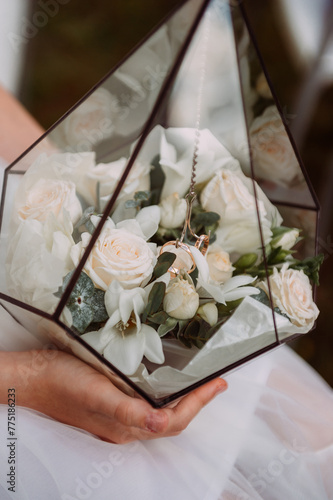 The image shows a hand holding a bouquet of white flowers, possibly roses, in an indoor setting 6899.