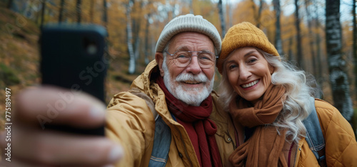 Happy senior couple taking selfie using smartphone in autumn time