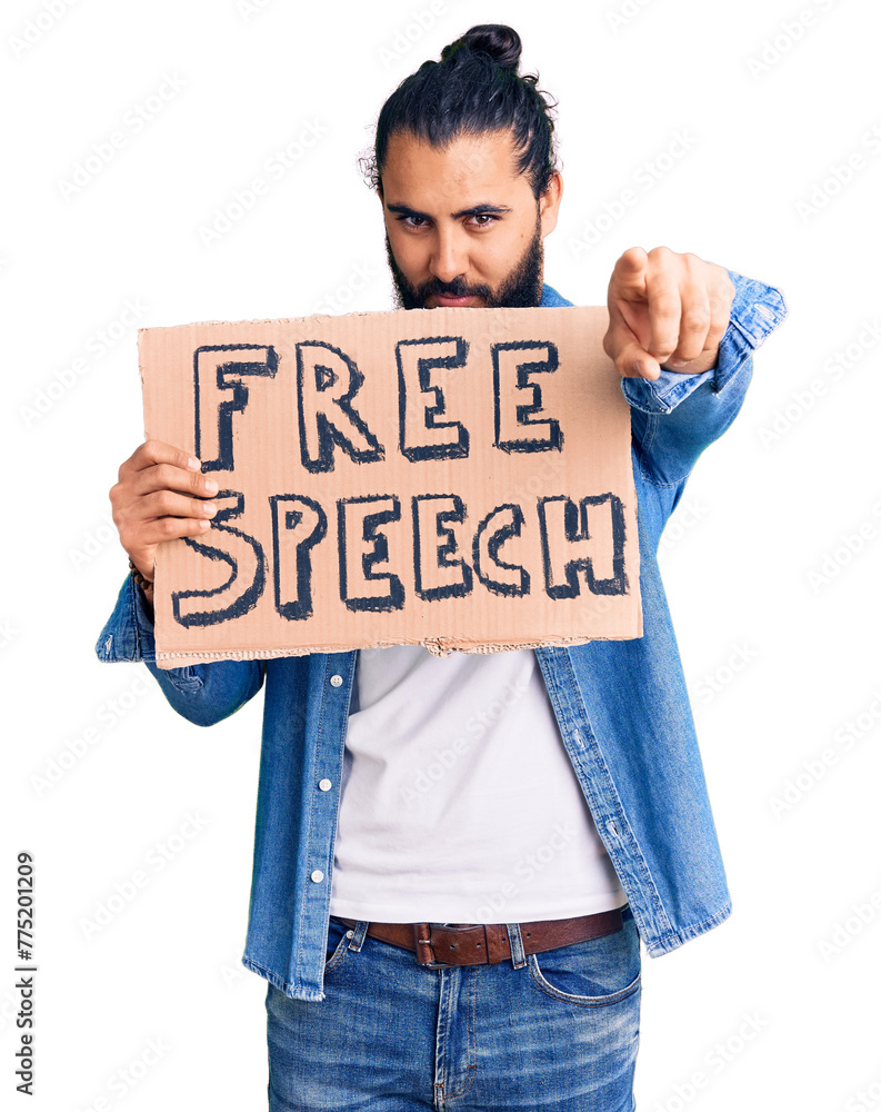 Young arab man holding free speech banner pointing with finger to the camera and to you, confident gesture looking serious Young arab man holding free speech banner pointing with finger to the camera and to you, confident gesture looking serious