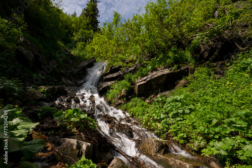 Mountain waterfall on the background of the sky with a summer sunny day.