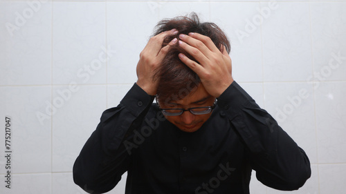 depressed young man sitting at the table and covering his face with his hands