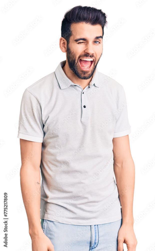 Young handsome man with beard wearing casual polo winking looking at the camera with sexy expression, cheerful and happy face. Young handsome man with beard wearing casual polo winking looking at the camera with sexy expression, cheerful and happy face.