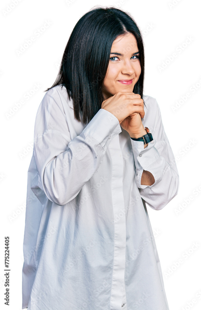 Young brunette woman with blue eyes wearing oversize white shirt laughing nervous and excited with hands on chin looking to the side Young brunette woman with blue eyes wearing oversize white shirt laughing nervous and excited with hands on chin looking to the side