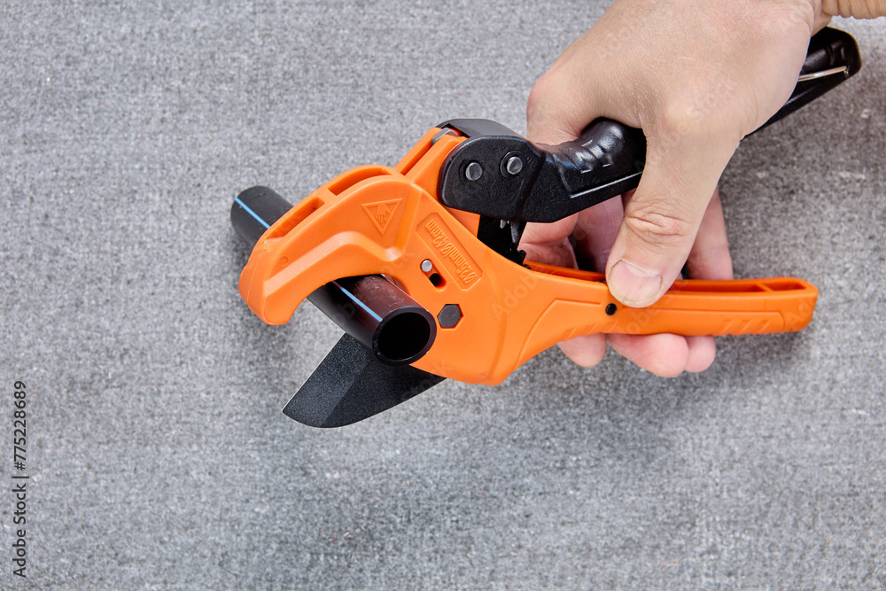 Pipe scissors cutter hand plumbing tool for cutting HDPE pipes, close-up on gray background. - obrazy, fototapety, plakaty 