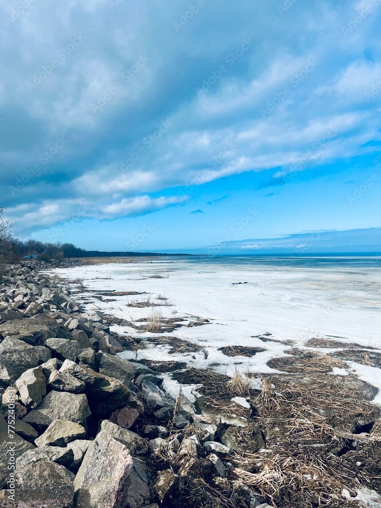 Fototapeta premium Frozen sea coast, ice at the sea, sea horizon, sky reflection on the water surface, natural colors