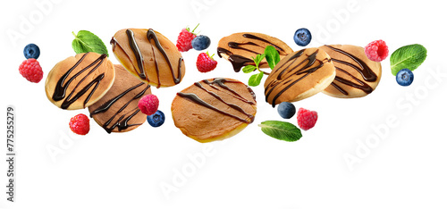 Flying pancakes and berries topped with chocolate syrup isolated on white