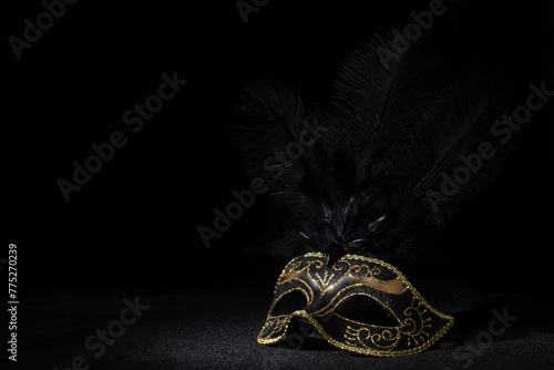 Carnival gold mask with feathers on black background.