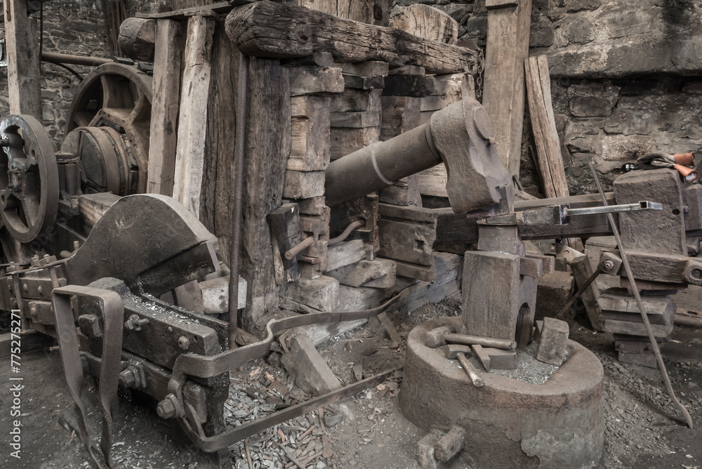 Historic machinery in a blacksmiths worksshop. - obrazy, fototapety, plakaty 