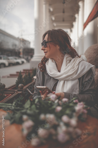 A charmig middle-aged woman wate the order a french cafe on a city street. A woman with flowers is enjoing a wonderful place photo