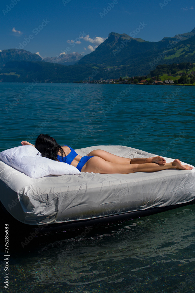 Fitness sexy female model Relaxing At Spa Resort. Sexy woman sleeping or resting on a mattress in the water. Water mattress concept. Summer rest.