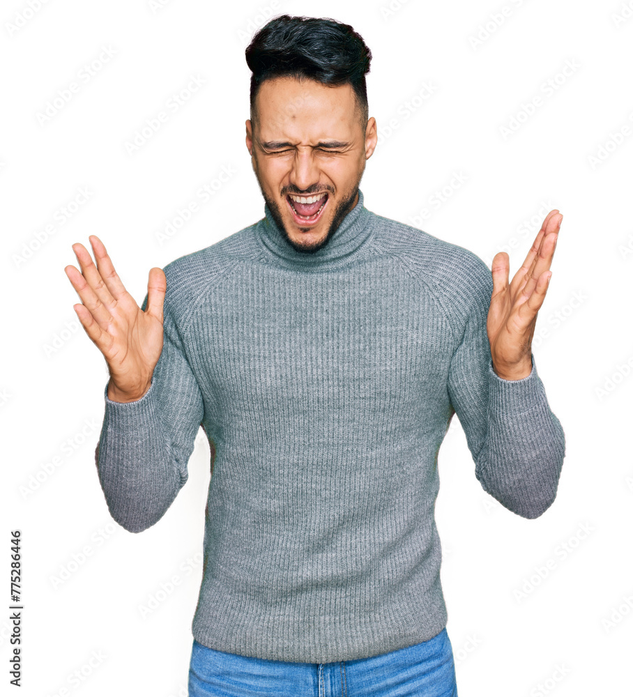Naklejka premium Young arab man wearing casual clothes celebrating mad and crazy for success with arms raised and closed eyes screaming excited. winner concept