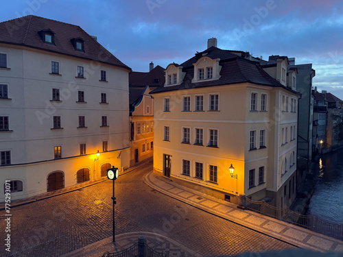 Night in Prague: An empty city street by Charles Bridge, cobbled square aglow with street lights.