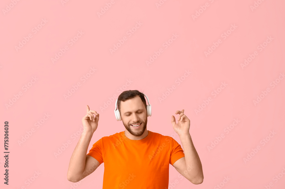 Young man in modern headphones pointing at something on pink background Young man in modern headphones pointing at something on pink background