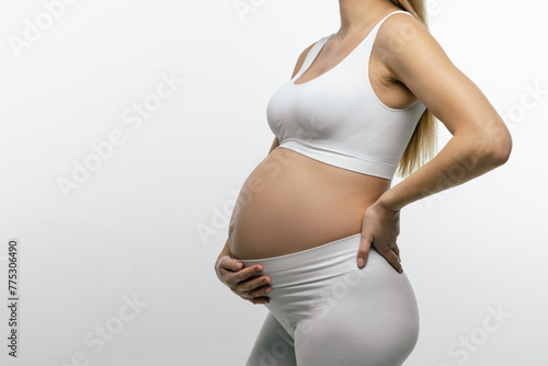 Pregnant woman in white top and leggings suffering from a lower back pain