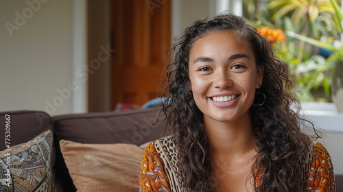 Young Maori woman sitting indoors at home on couch photo