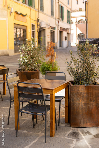 Outdoor street cafe tables ready for service. Empty cafe terrace with wooden table and plastic chair, morning time. Food concept © mdyn