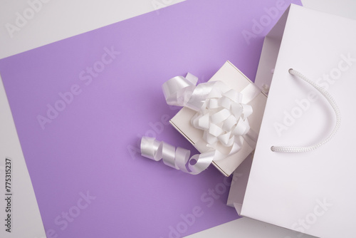 Festive surprise, white gift box, top view, decorated with white ribbon on a colored background. Place for text, holiday card