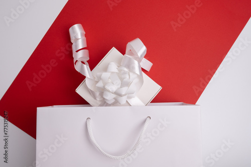 Festive surprise, white gift box, top view, decorated with white ribbon on a colored background. Place for text, holiday card