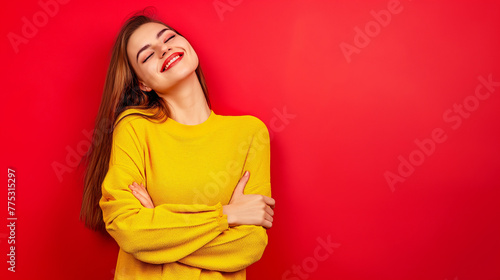 Mulher sorrindo de braços cruzados vestindo amarelo no fundo vermelho