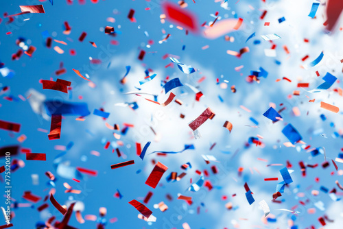 Red, white, and blue confetti joyfully scattered against a clear blue sky © Mirador
