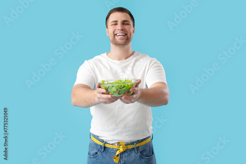 Young man with salad on blu...