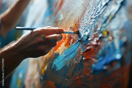 An artist's hand holding a brush to a colorful, textured canvas, showcasing creativity and the artistry of painting