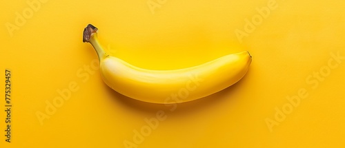  A yellow banana on a yellow surface with a black spot on the stem's top