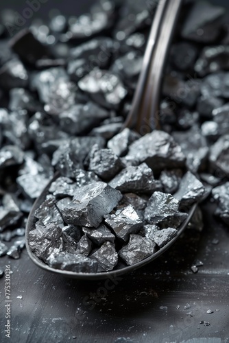 Close-up of a ladle filled with metallic zinc ore against a moody, dark background photo