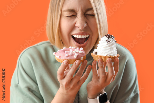 Beautiful woman with treats on orange background  closeup. Overeating concept