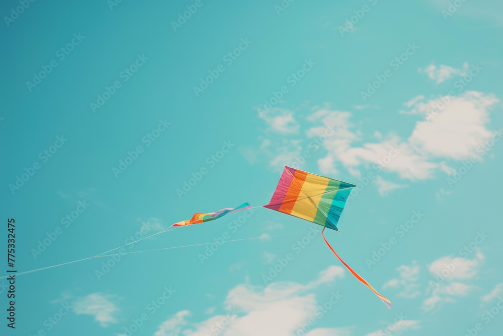 Colorful raindbow kite flying in blue sky with fluffy clouds