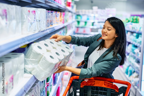 Happy woman buying toilet paper in supermarket.