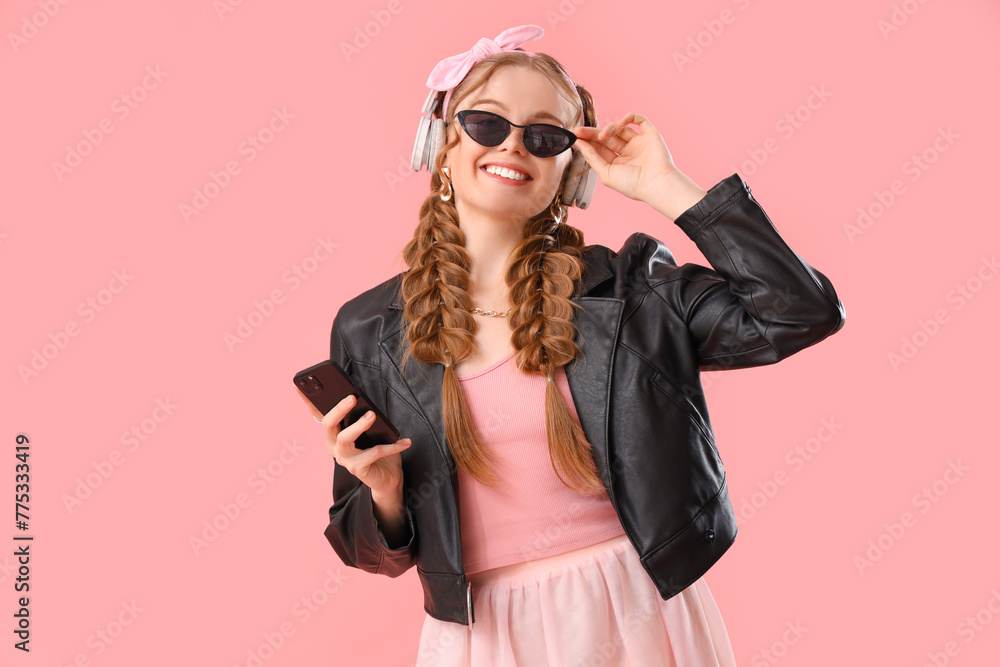 Happy smiling young woman in headphones with braids and mobile phone on pink background Happy smiling young woman in headphones with braids and mobile phone on pink background