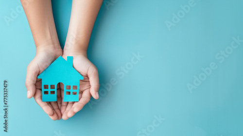 Cyan blue paper house in the hands of a child. Real estate, housing