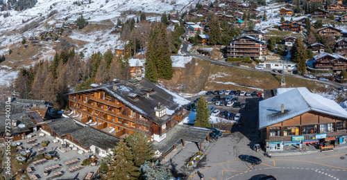 Aerial panoramic view of the Verbier ski resort town in Switzerland. Classic wooden chalet houses standing in front of the mountains.  © Aerial Film Studio