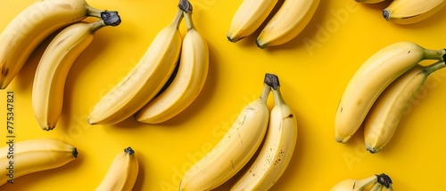   A group of bananas resting on a yellow table beside a cluster of bananas on the same table