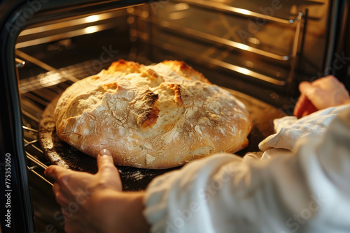 Person Taking Freshly Baked Bread Out of Oven in Home Kitchen