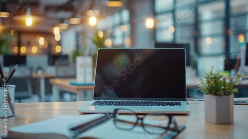 Serene office scene: laptop computer, notebook, and eyeglasses on desk in spacious workspace post work hours