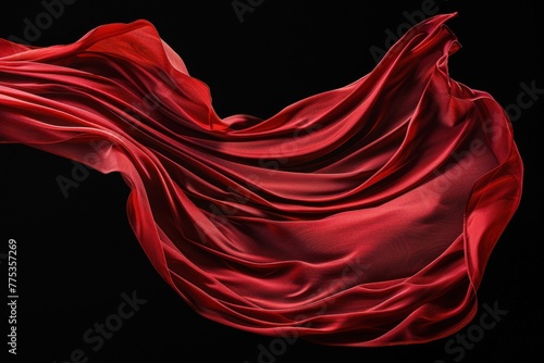 Red drape falling like wings isolated on flat black background. Beautiful red fabric with pleats floats in air