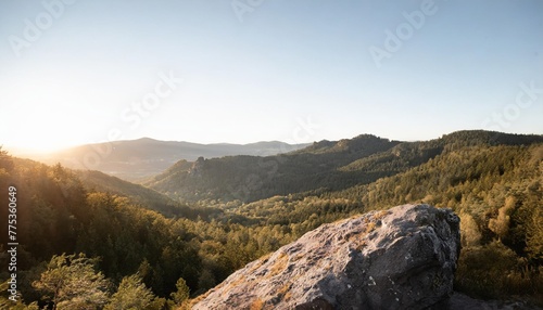 clean nature in the big forest image of a mountain range with lush forests and a clear sky there is a large rock in the picture you ll feel refreshed when you see it and want to go on a vacation photo