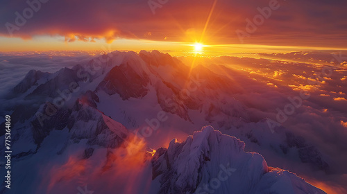 Fiery sunrise over snow-capped mountains, long shadows in valley