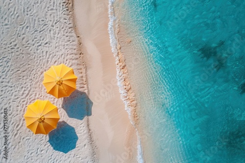 View from above a tropical beach with white sand and azure sea shore, two beach umbrellas on the beach