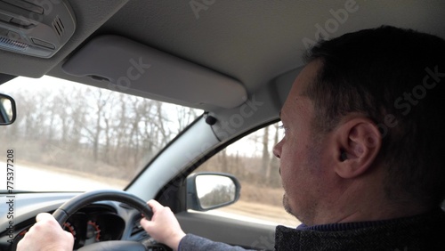 Pensive man driver riding car with hands on steering wheel back side view closeup. Confident modern male speed traffic driving automobile travel transportation at countryside highway autumn landscape © SUPER FOX