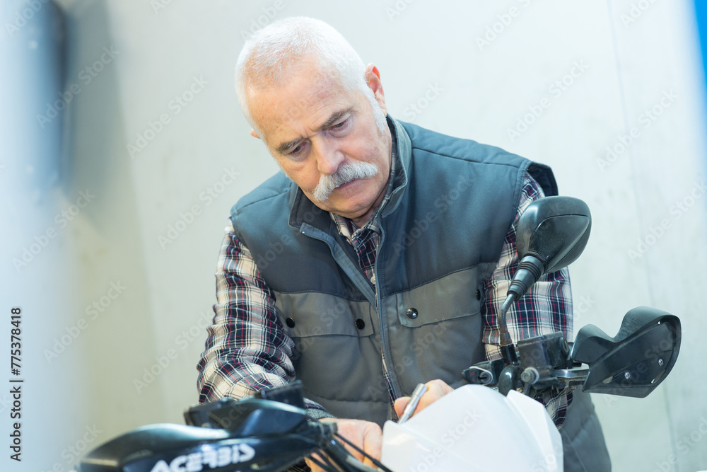 a senior man repairing motorbike outdoor a senior man repairing motorbike outdoor